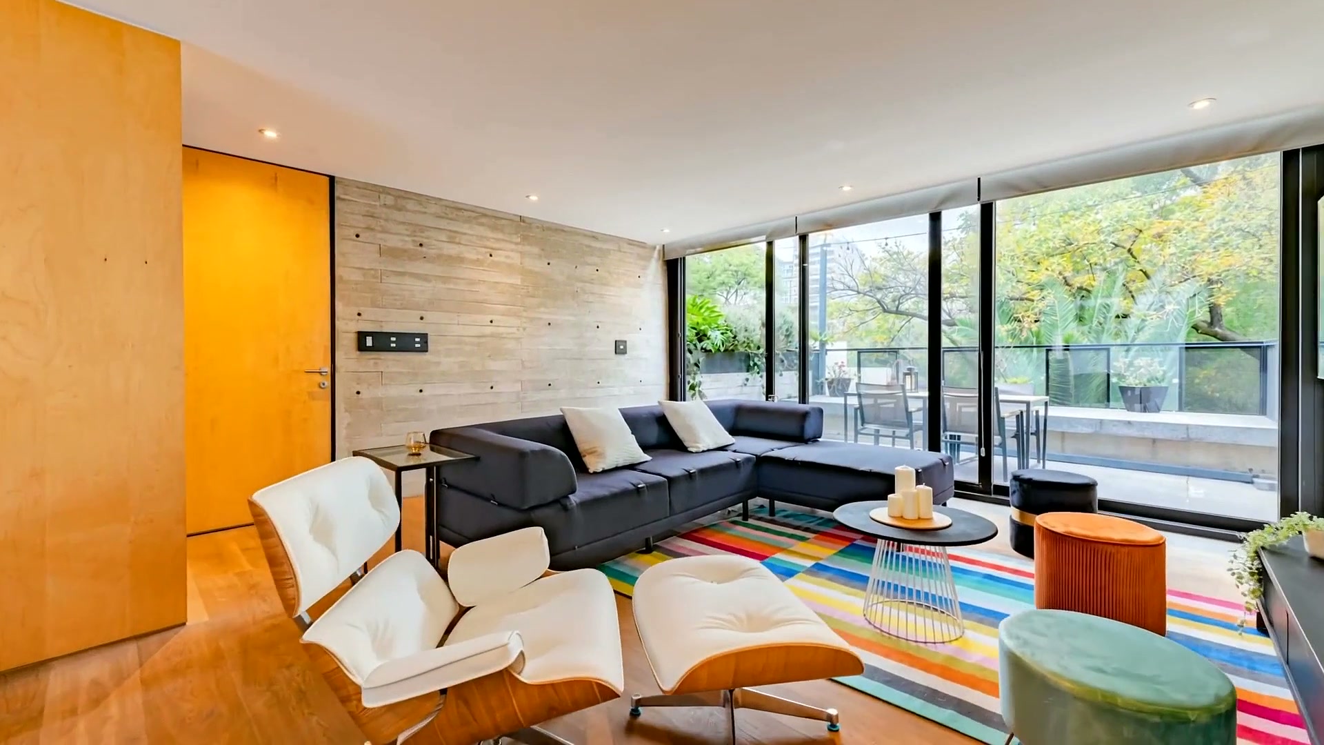 Sala con muro de concreto aparente y ventanal a la terraza